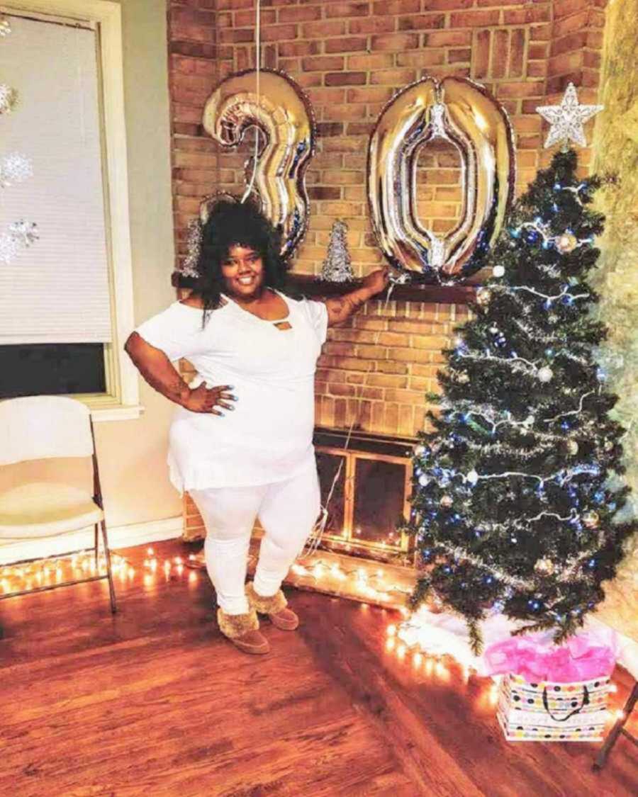 Woman poses next to birthday balloons and Christmas tree