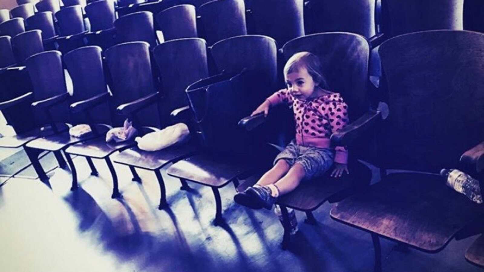 toddler sits in front row theater seat