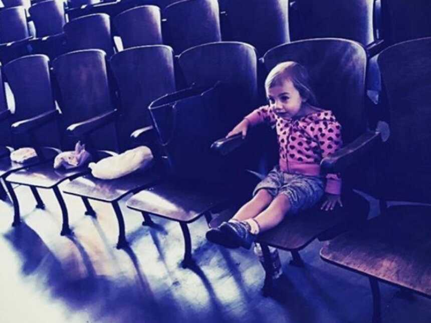 toddler sits in front row theater seat
