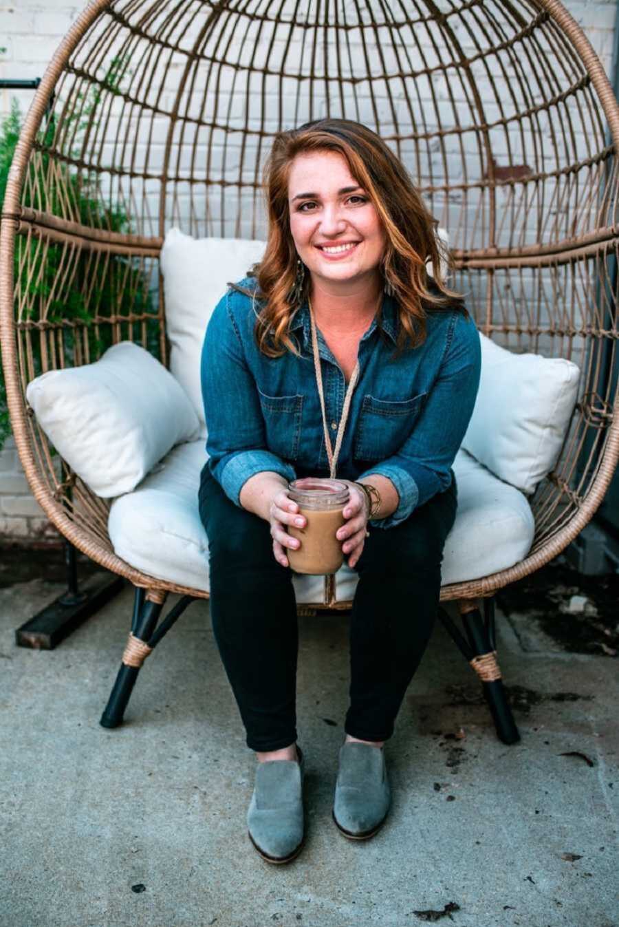 woman sitting on patio chair smiling while holding drink