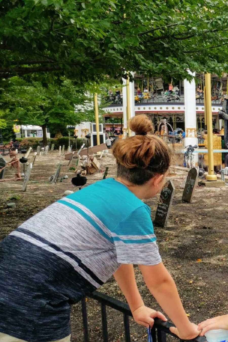 boy with long hair in a bun while wearing blue shirt