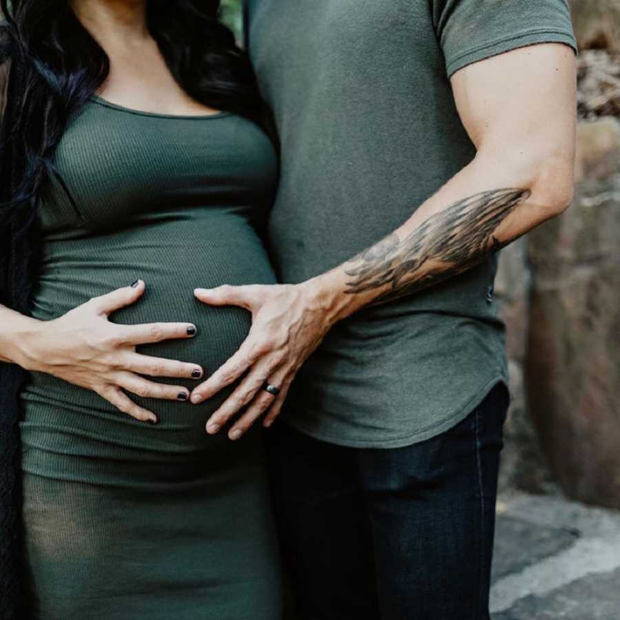 husband and wife placing hands on her pregnant belly