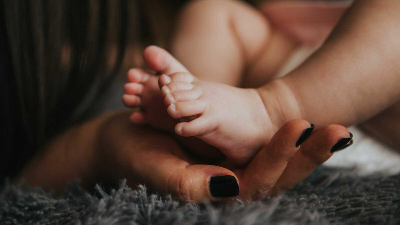 baby's feet sitting in woman's hand