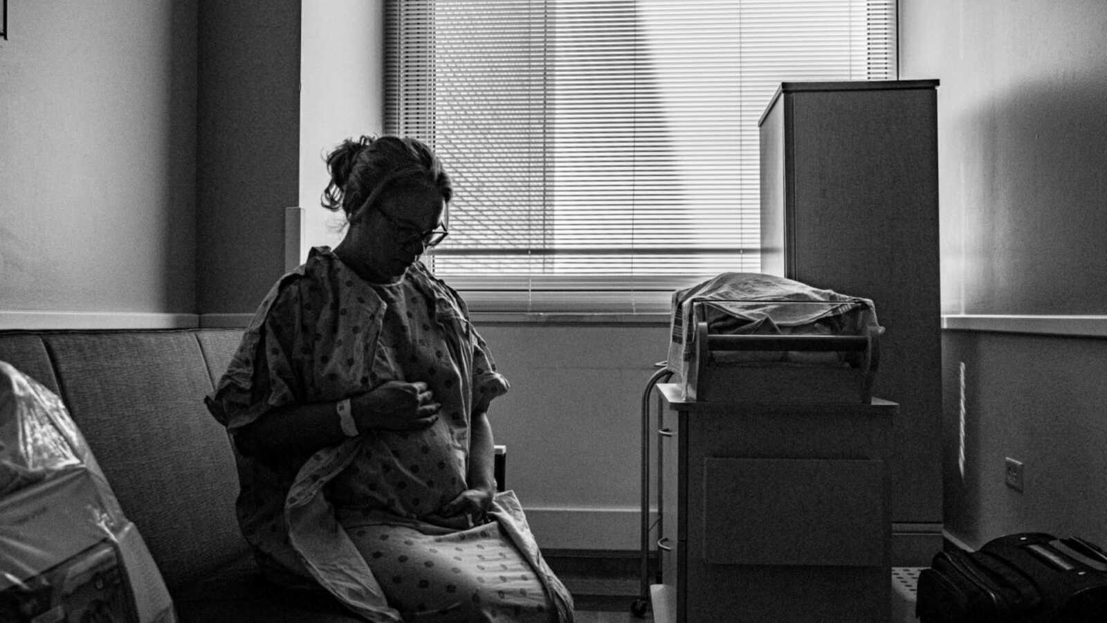 pregnant woman wearing hospital gown sitting in hospital room
