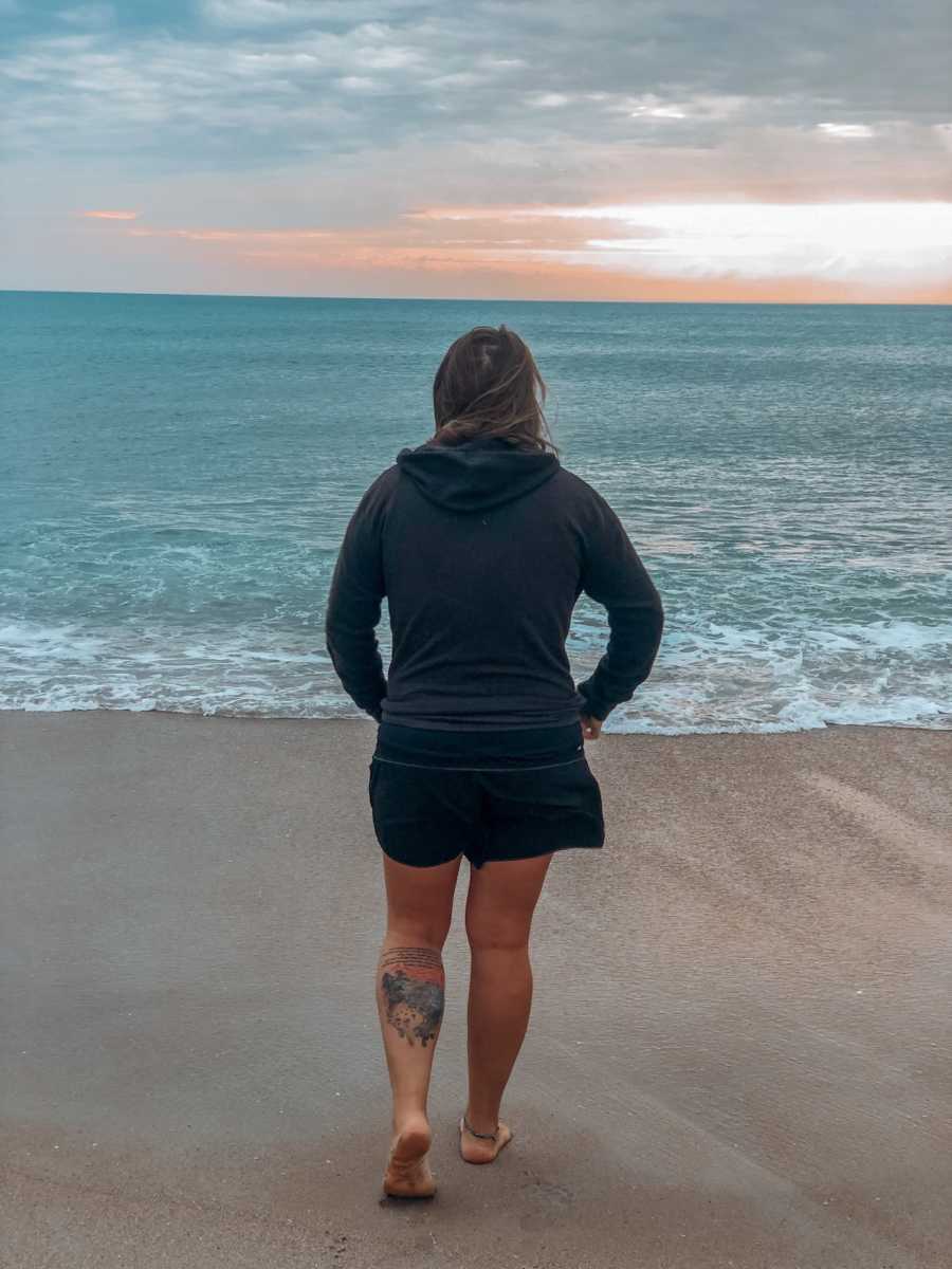 adoptee and birth mother stands facing out to the ocean