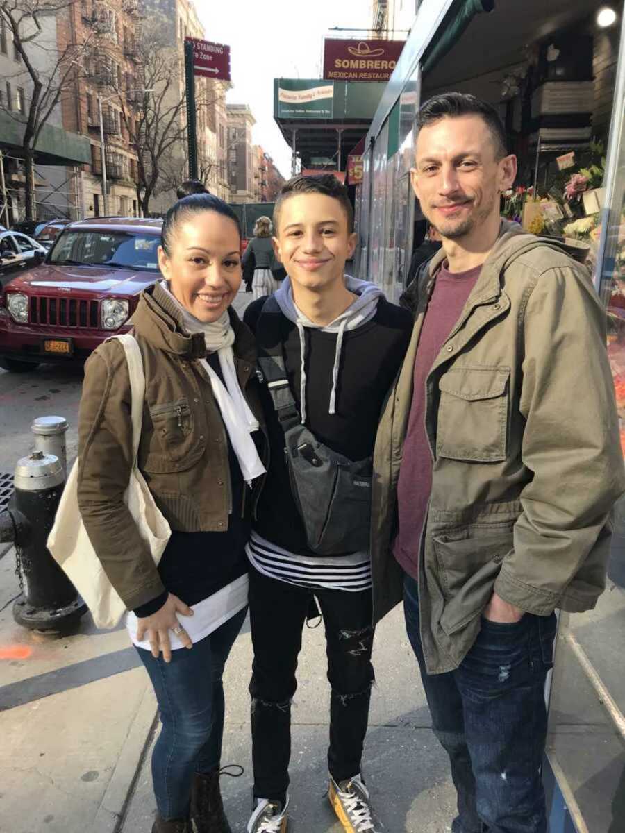 Adoptive parents and son standing on NYC sidewalk