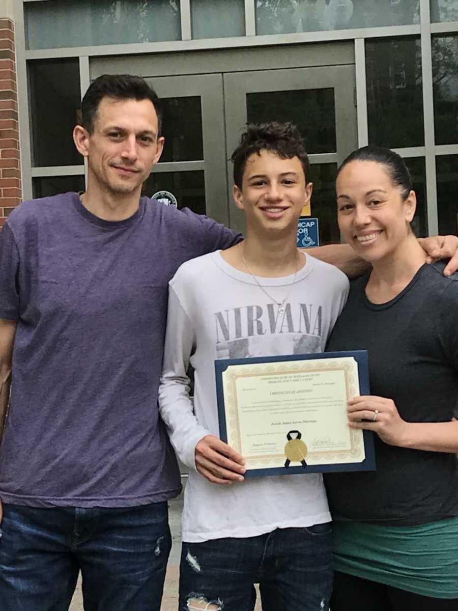 Adopted son holding official adoption papers next to parents
