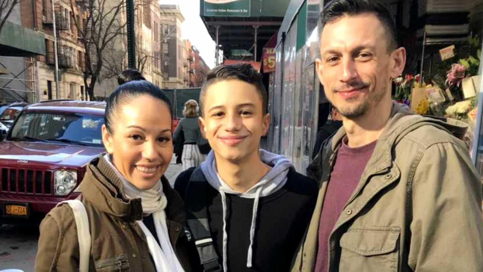 Son smiling next to adoptive parents on NYC street