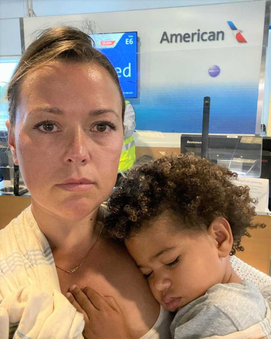 Teary-eyed mom holds newborn at airport
