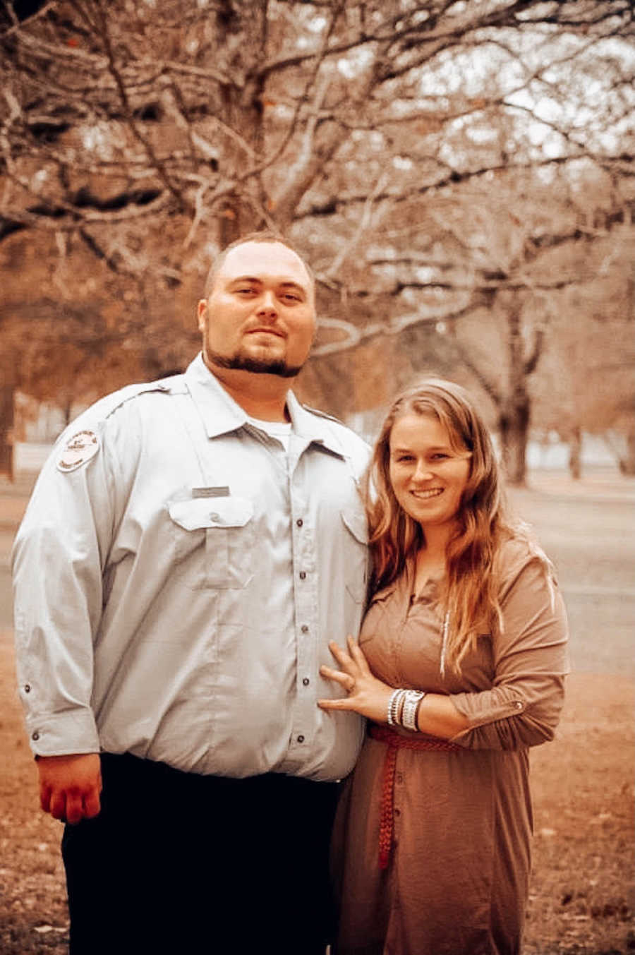 husband and wife stand together, arms around each other