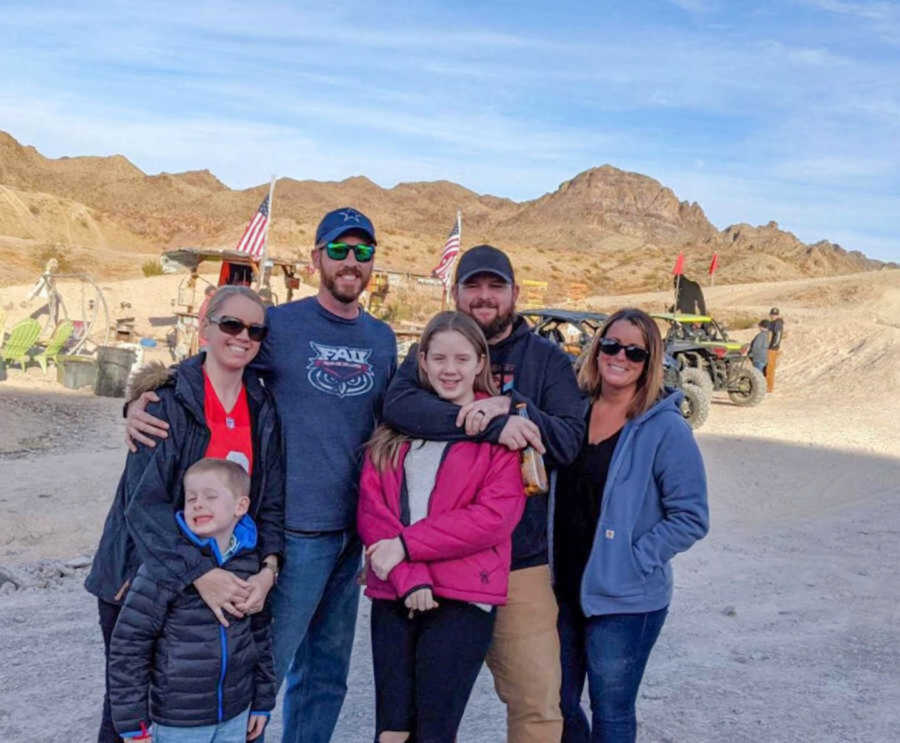 Blended family pose for photo while standing in dirt