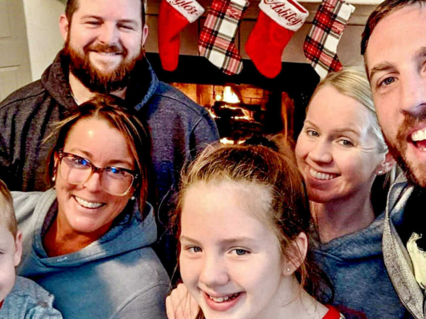Family smiling in front of Christmas stockings and fireplace
