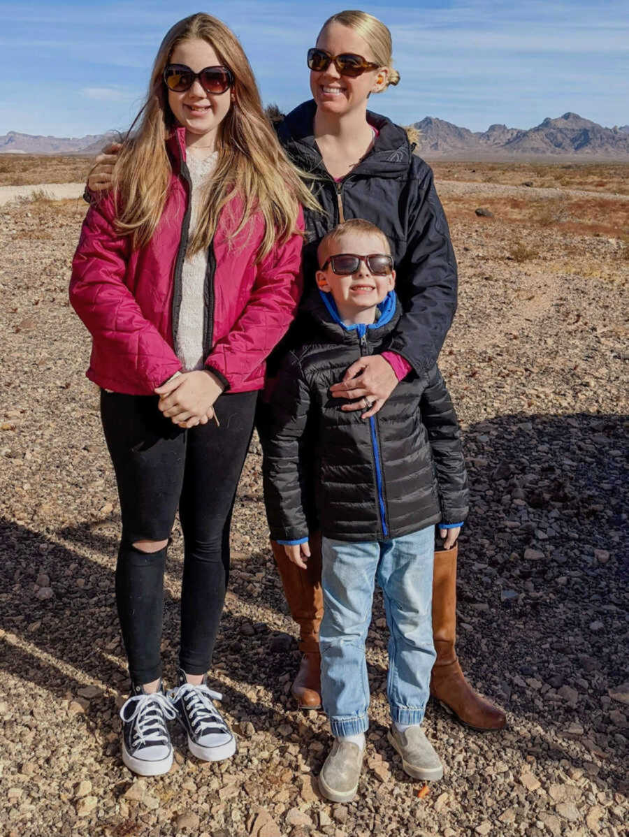 Stepmom and birth mom in sunglasses smile with son