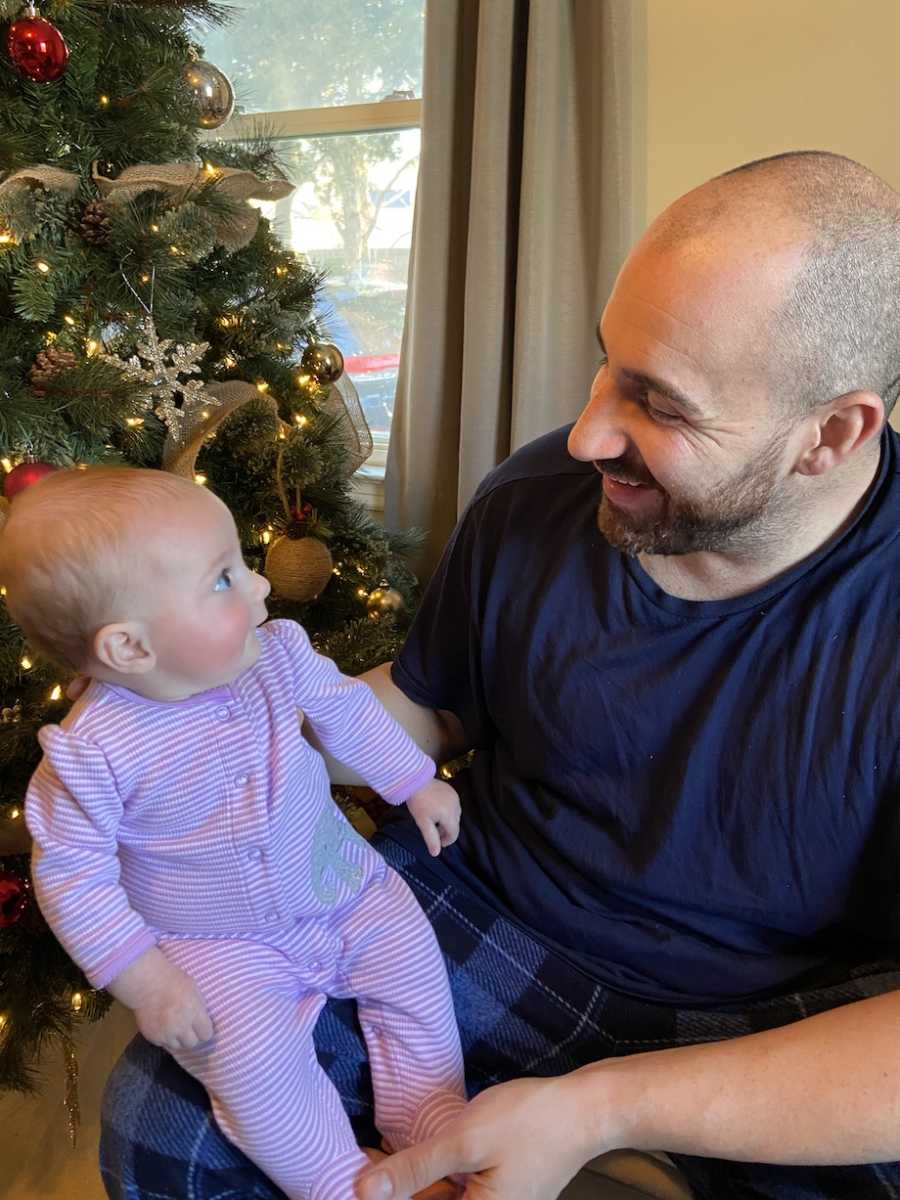 father looks lovingly at his daughter while she is sitting on his lap