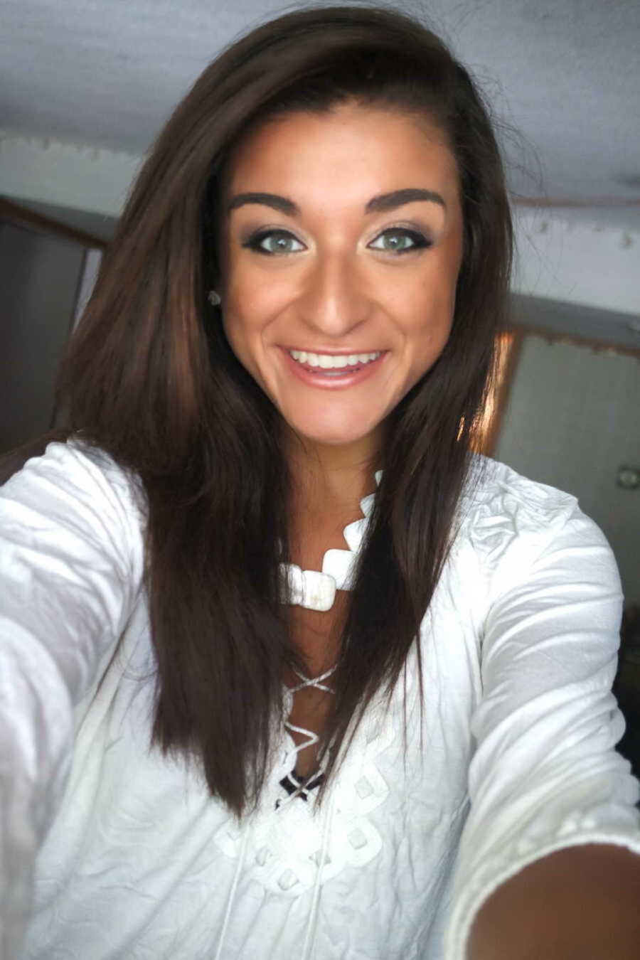 woman in white shirt smiles in selfie