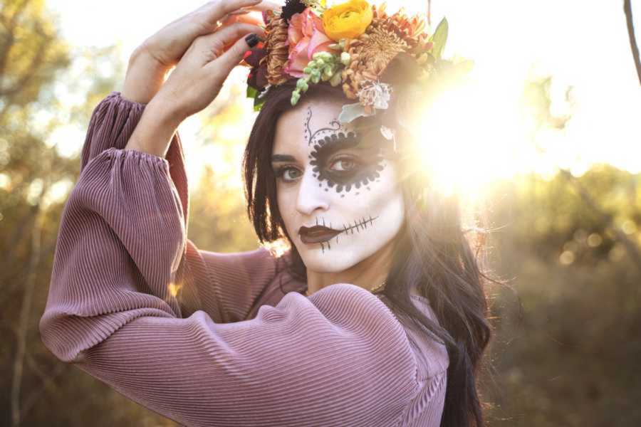 woman poses with face painted like a skull