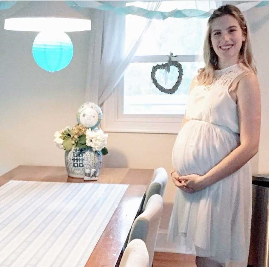 Teen mom in white dress holds pregnant belly