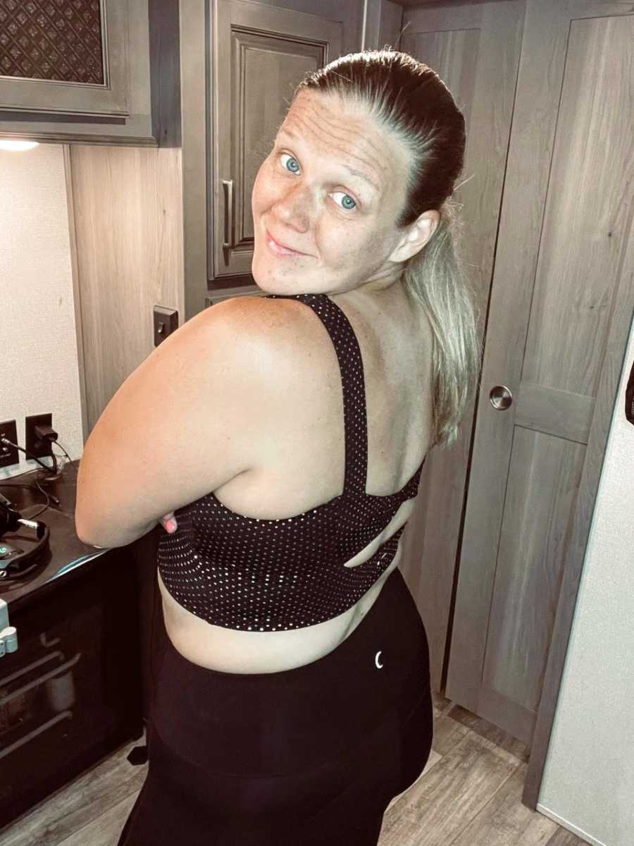 Plus-sized woman in black leggings and black crop top smiles for camera