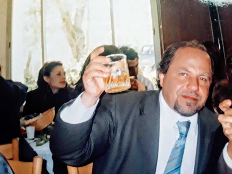 Man in suit battling addiction holds cup of alcohol