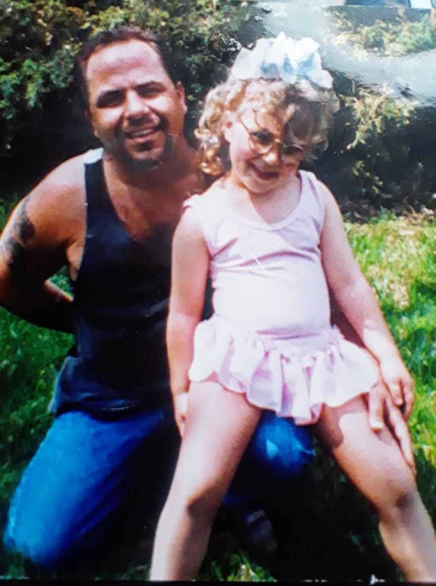 Girl in pink dress and glasses sits on father's lap