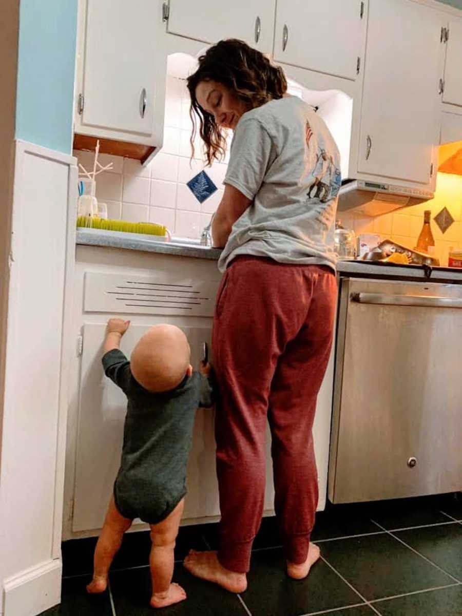 Mom in red sweatpants smiles at toddler in green shirt