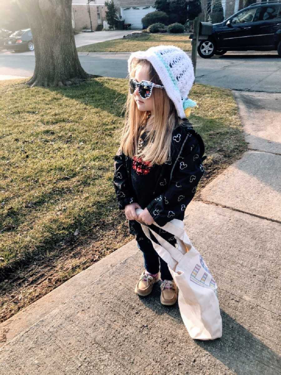 sassy little girl confidently dressed stands on sidewalk