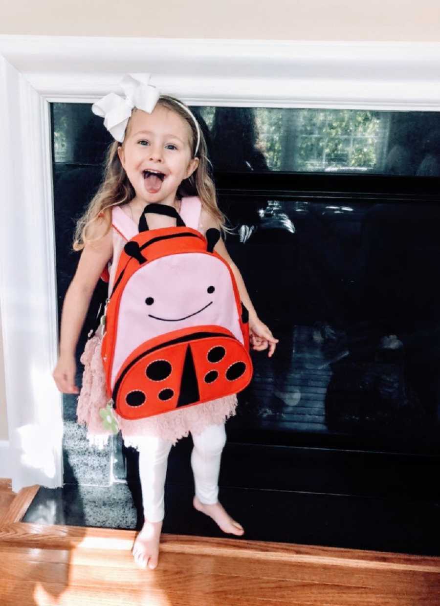 silly little girl wears her backpack backwards and sticks her tongue out