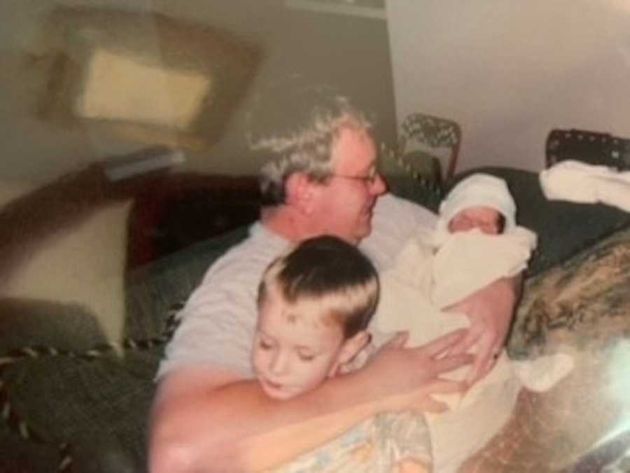 Dad holding newborn son and toddler