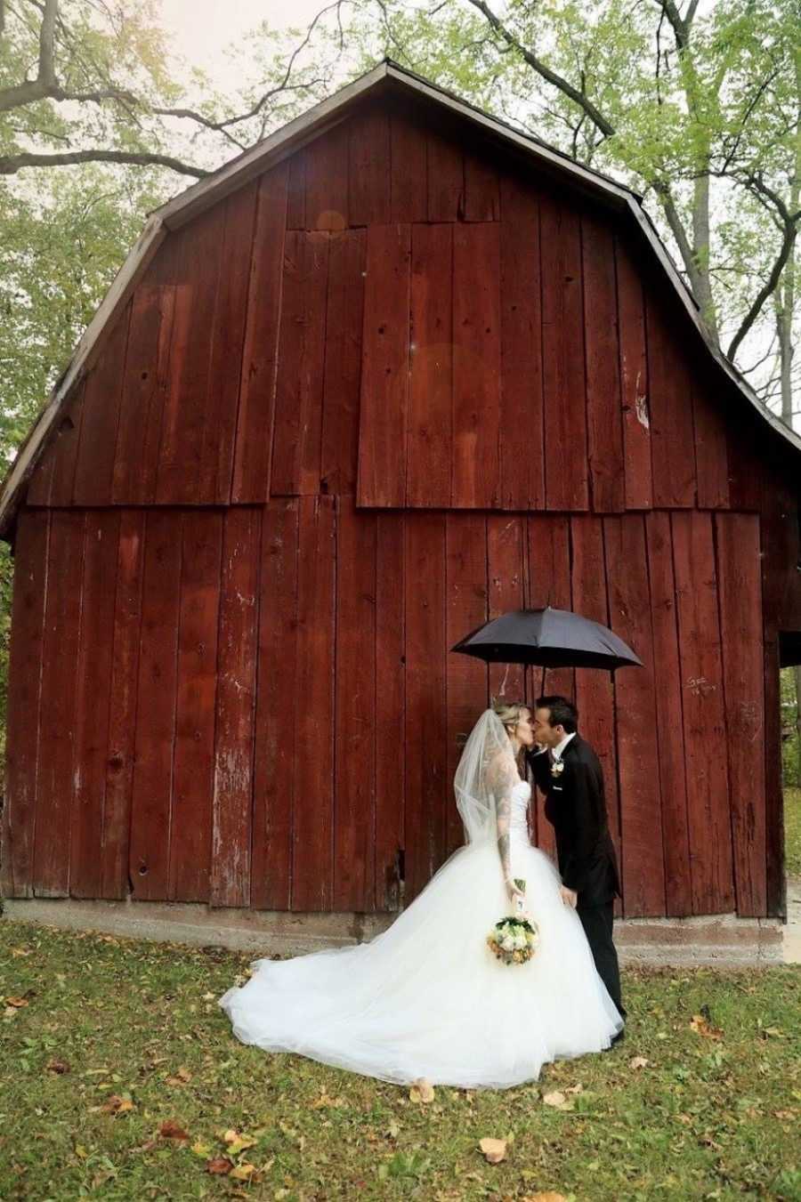 Wedding photos at barn with umbrella and wedding dress