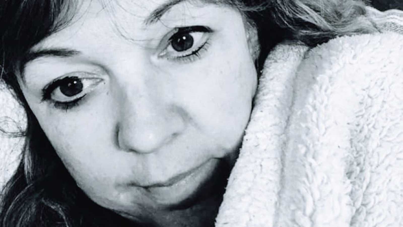 Woman takes serious selfie while curled up in a fluffy blanket to advocate for mental health during the pandemic
