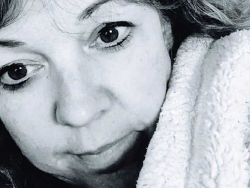疫情期间，一名妇女蜷缩在松软的毯子里认真自拍，以倡导心理健康