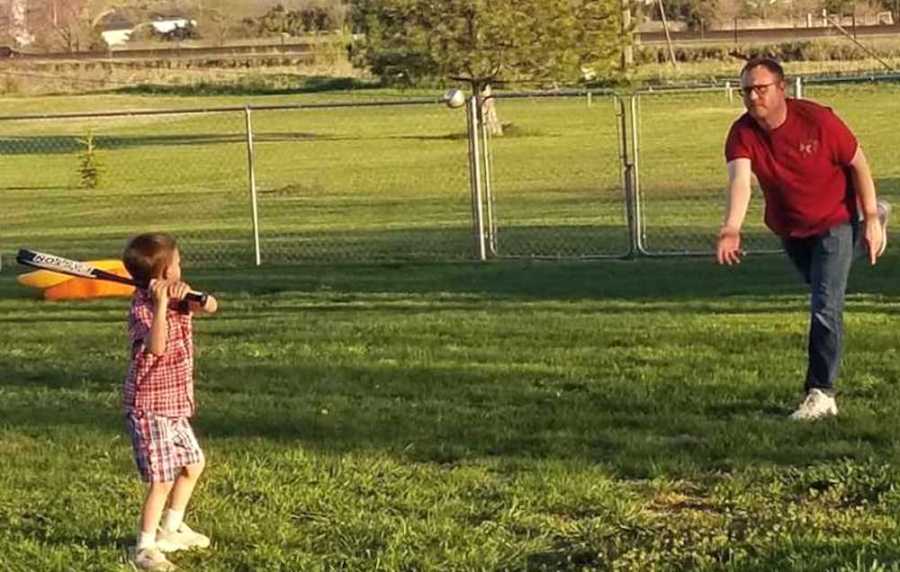 A little boy playing baseball with his dad