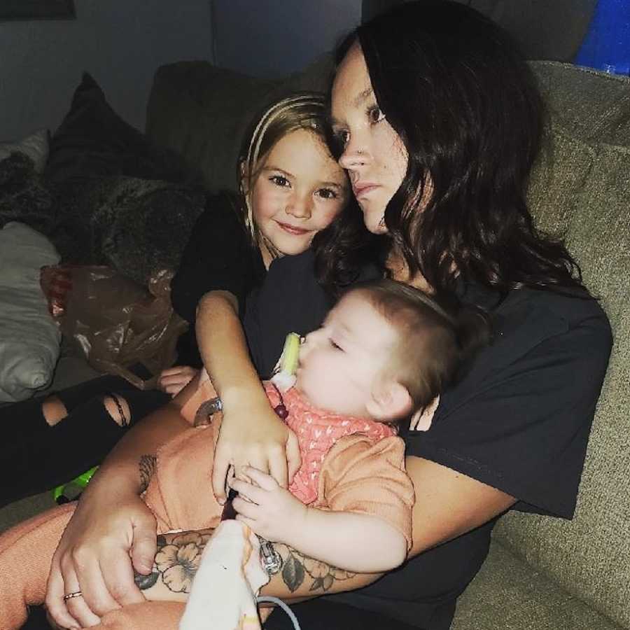 Mom holding daughters on couch