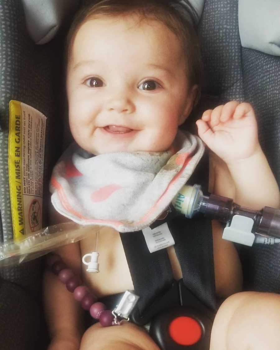 Baby with tracheostomy smiling in carseat