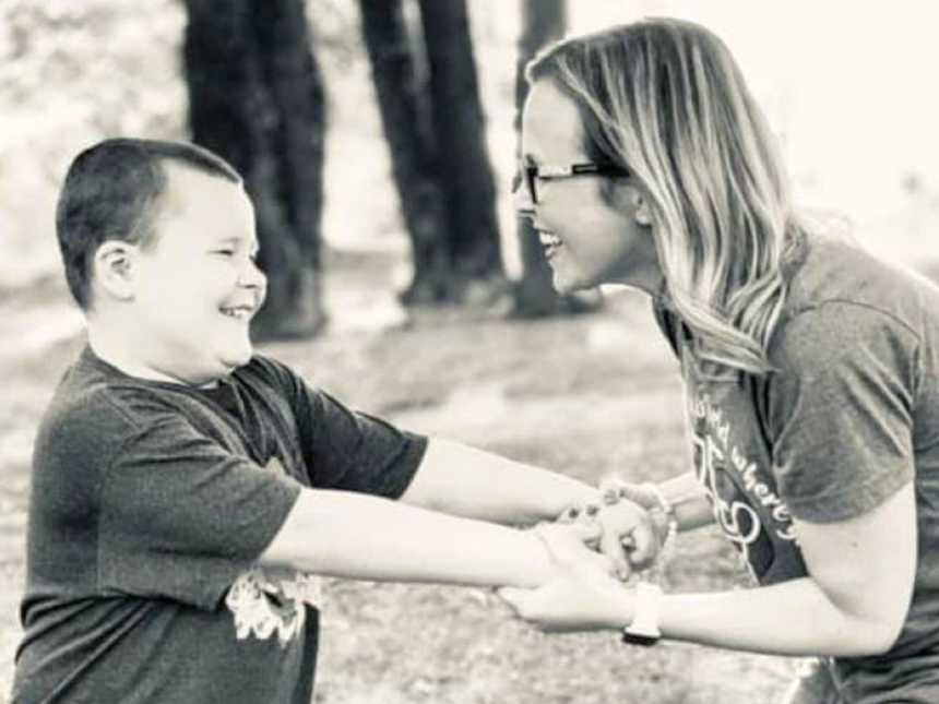 在一张全家福照片中，男孩妈妈和她患有自闭症的儿子手牵着手微笑着
