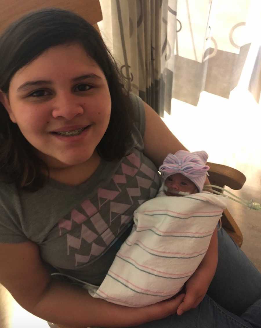 Teen holding newborn triplet sister