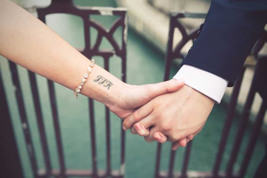 Husband and wife holding hands with visible tattoo