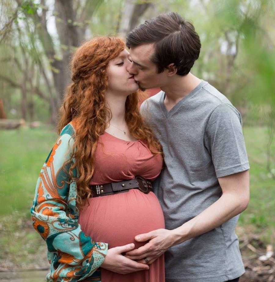 pregnant woman and husband embracing and kissing