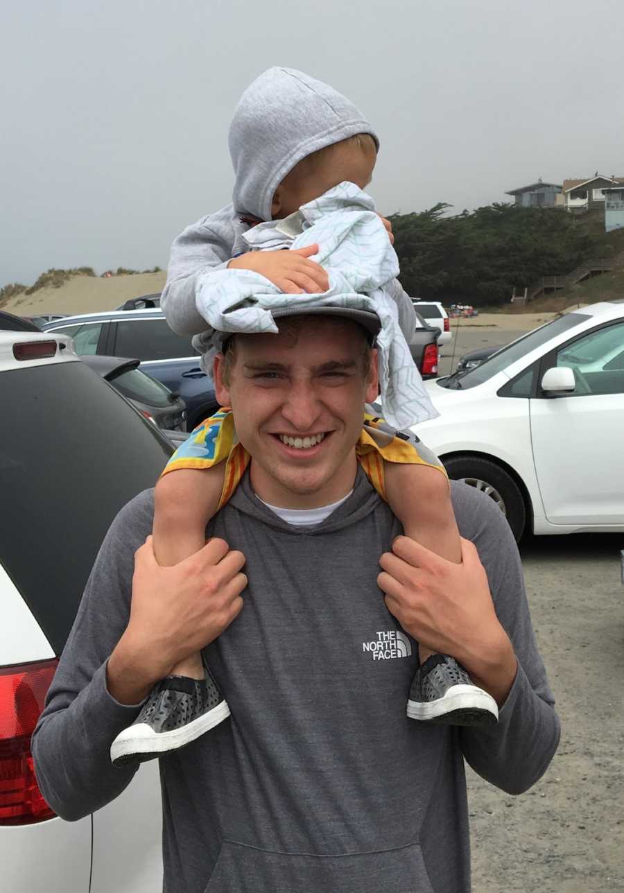 young man holding child on shoulders