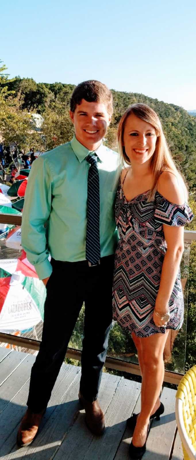 Couple smile and pose for a quick photo while dressed up for a rehearsal dinner