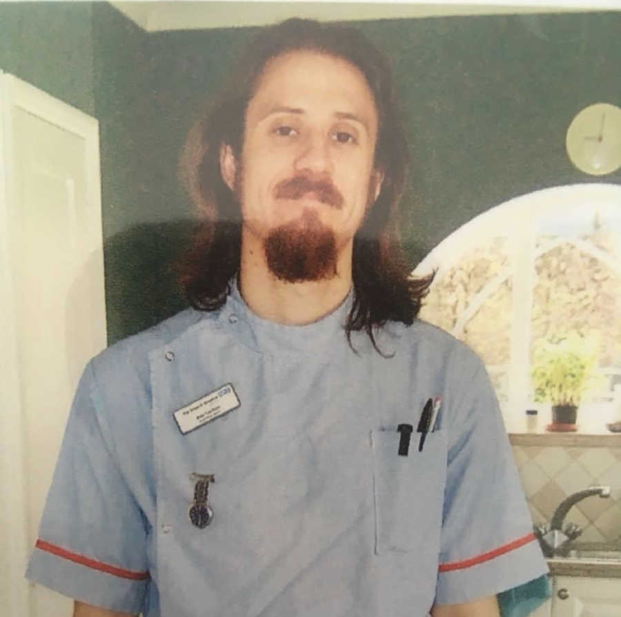 Man with long hair and beard in nurses uniform