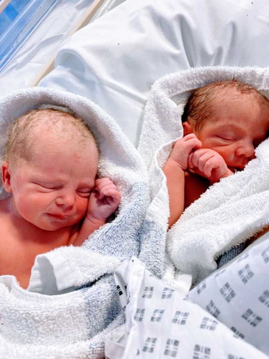 Newborn twins sleep while wrapped up in blankets at the hospital