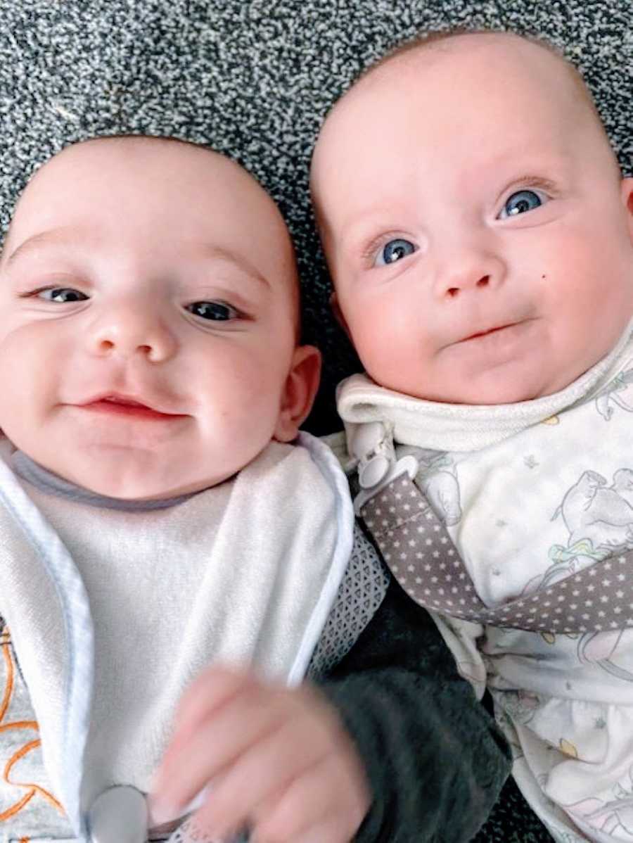 Mom snaps a close-up photo of her baby twins while they lay on the carpeted floor