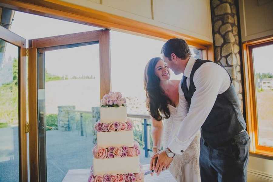 Newlywed couple cutting their wedding cake