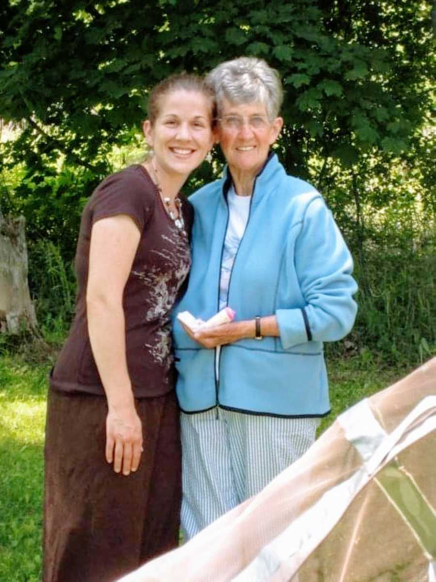 Woman smiles and poses with grandmother at outside event