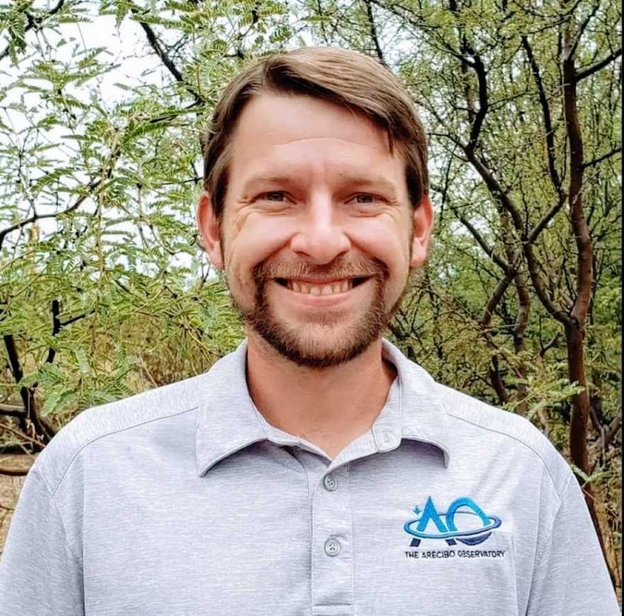 Man with UCF Arecibo Observatory shirt on smiles for a headshot