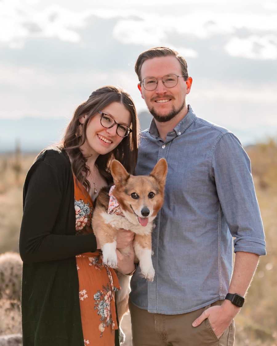 Woman poses for a family photo with her fiancé and their Corgi