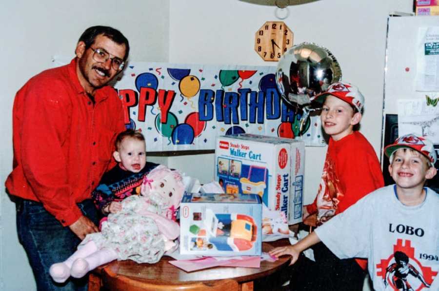 Three siblings pose with their father at a family birthday party