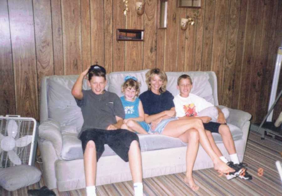Family shot of a mom with her daughter and two sons sitting on a couch together, smiling