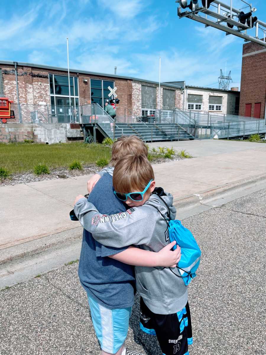 Two brothers hug each other while taking an outside stroll